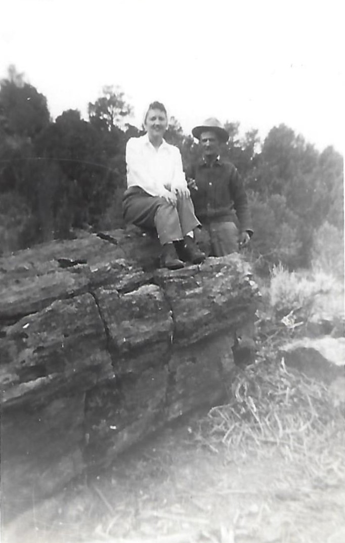 Evelyn Guerrero sitting on and James Guerrero standing by a petrified log in Motoqua, Utah