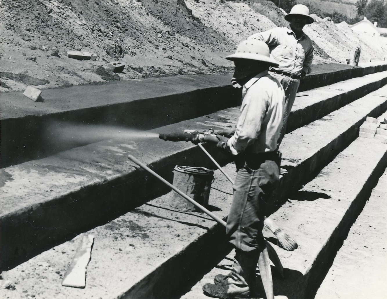 A man (LeGrand Frei?) spraying gunite on the cement benches of the new Dixie Sun Bowl