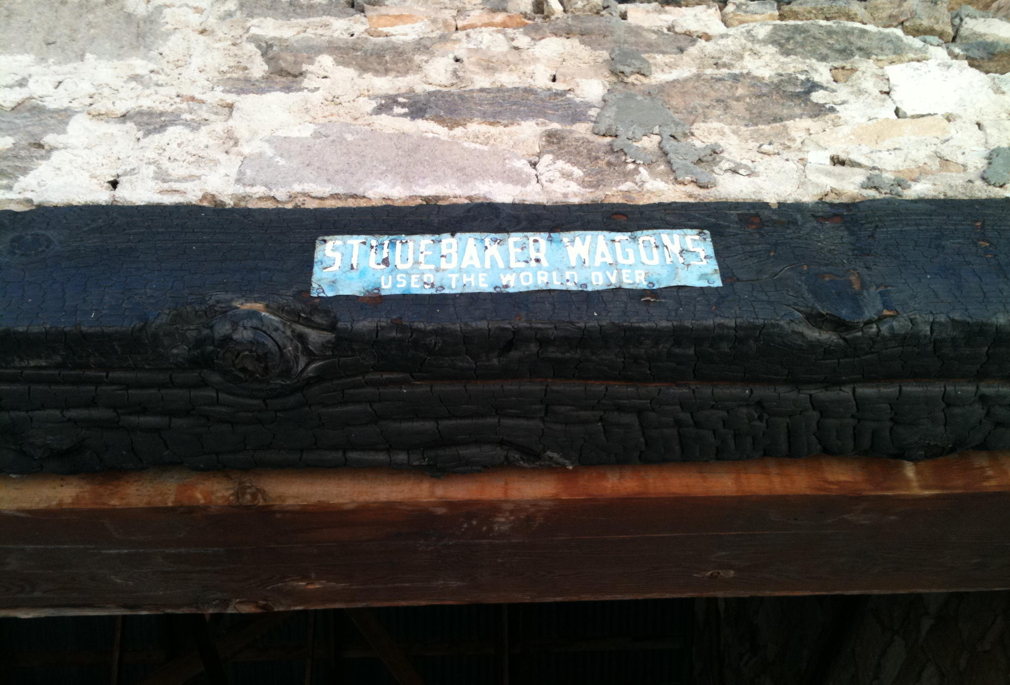 Burned beam and Studebaker Wagons sign in the stone barn on the Terry Ranch