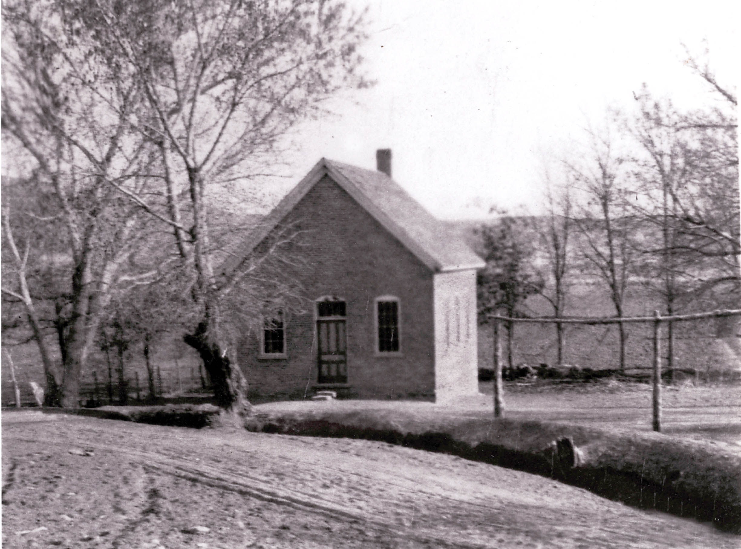 Old Bloomington Schoolhouse with an irrigation ditch out in front