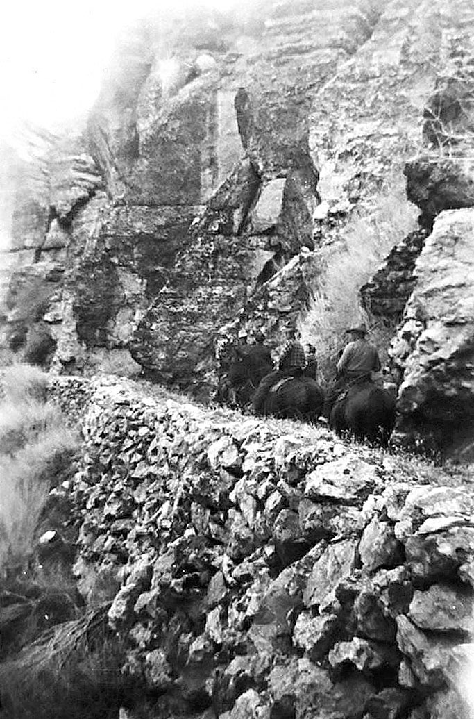 Men on horses and a rock wall
