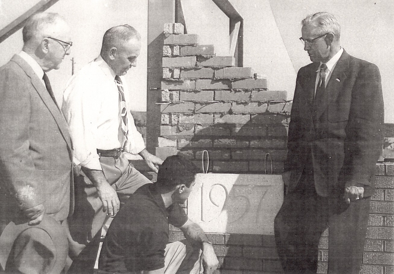 Four men laying the cornerstone of the new fieldhouse (gym)