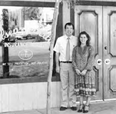 Two people standing in front of the Olsen-Leavitt Insurance Agency