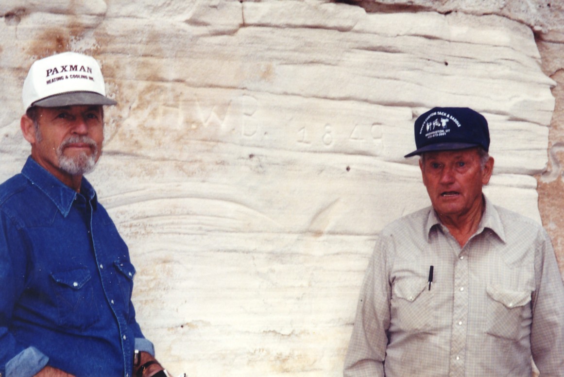 Two men in front of a rock with Henry W. Bigler's initials and 1849 carved in it