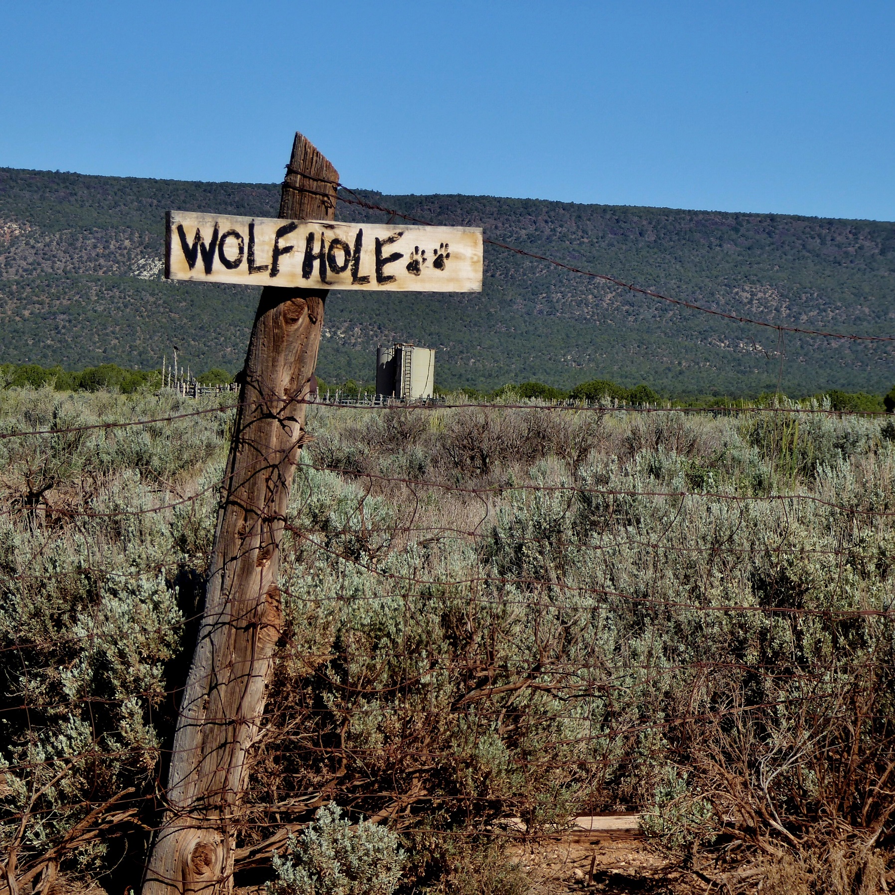 The Wolf Hole sign with a water tank in the background