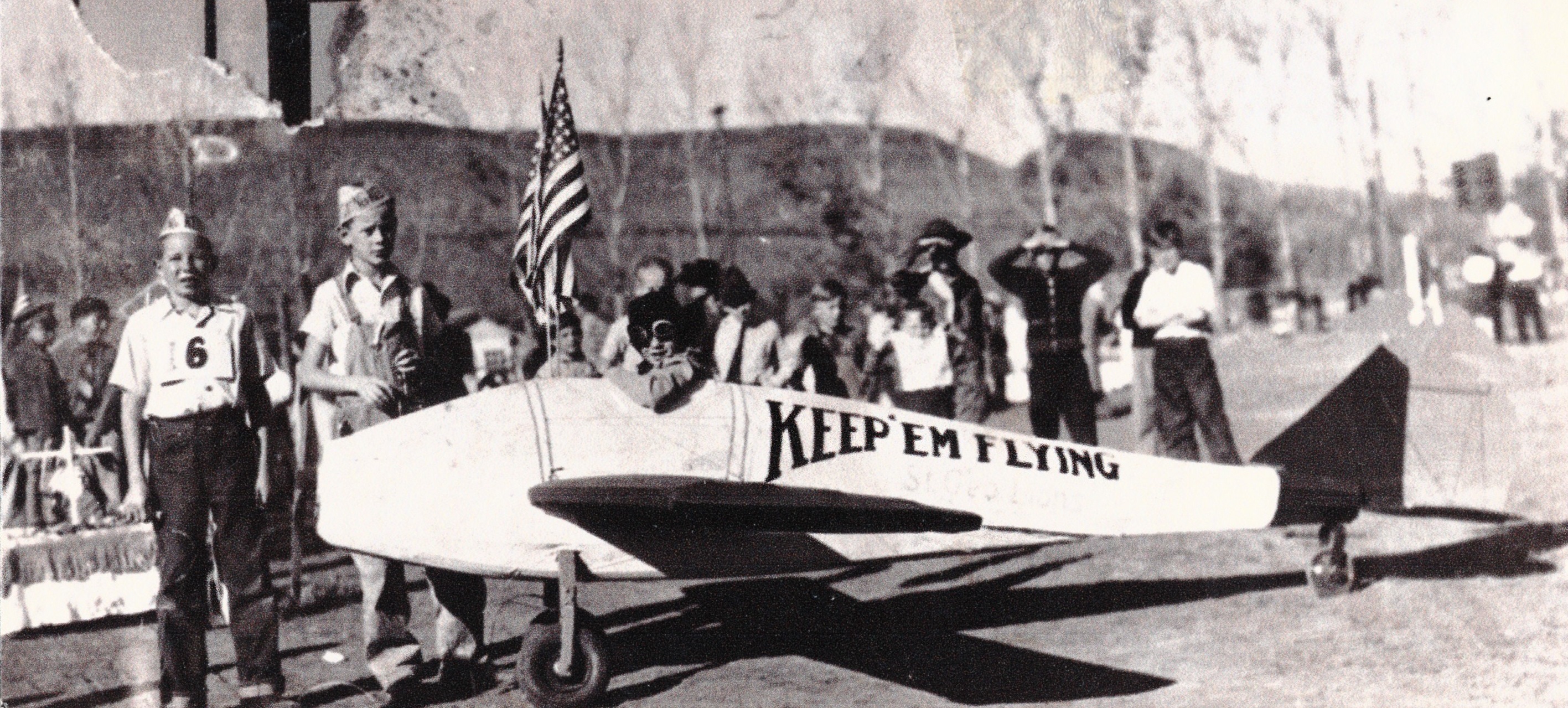 kids with a model airplane in what looks like a patriotic parade