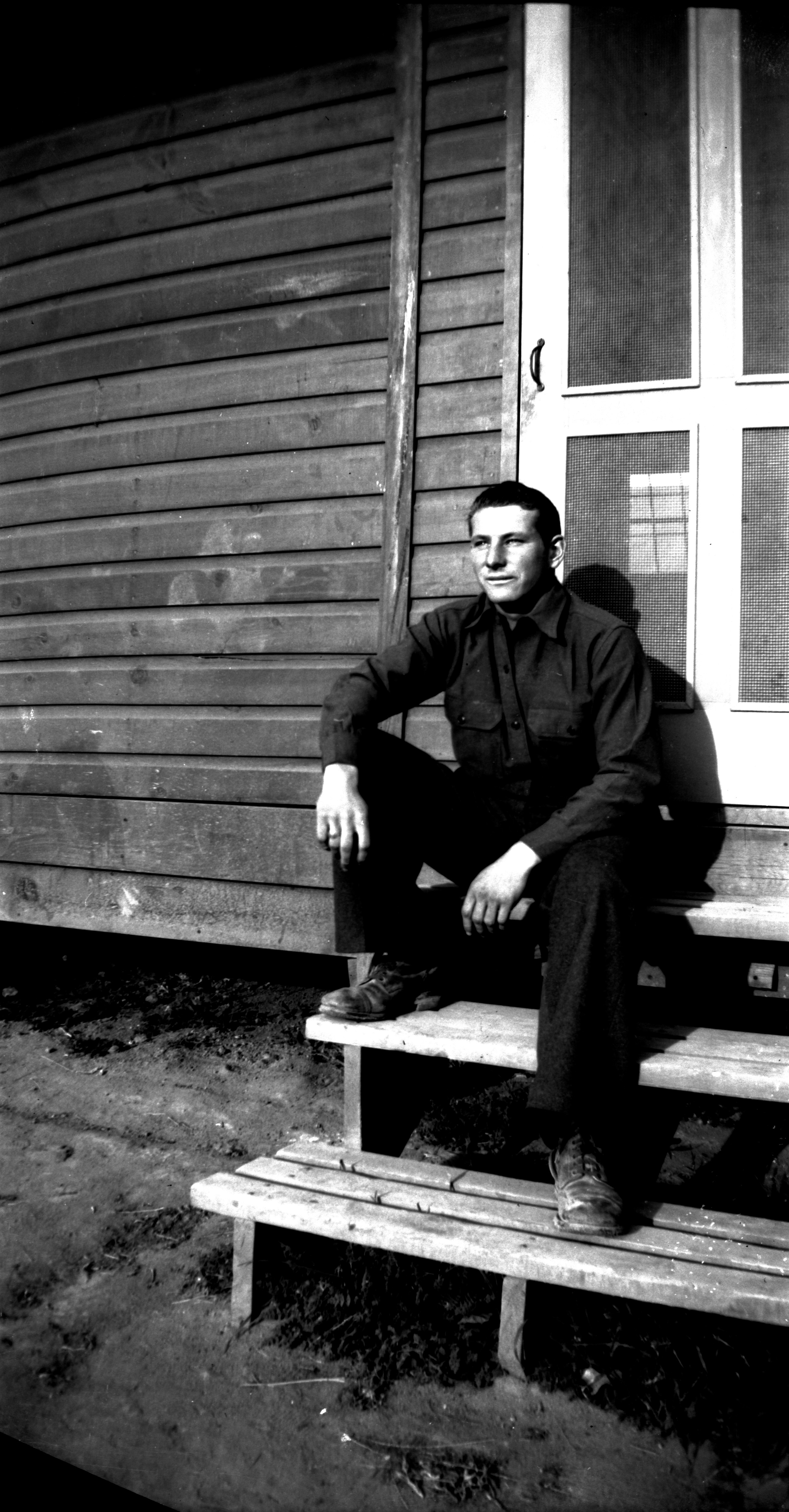A man sitting on wooden steps to a building at the Leeds CCC Camp