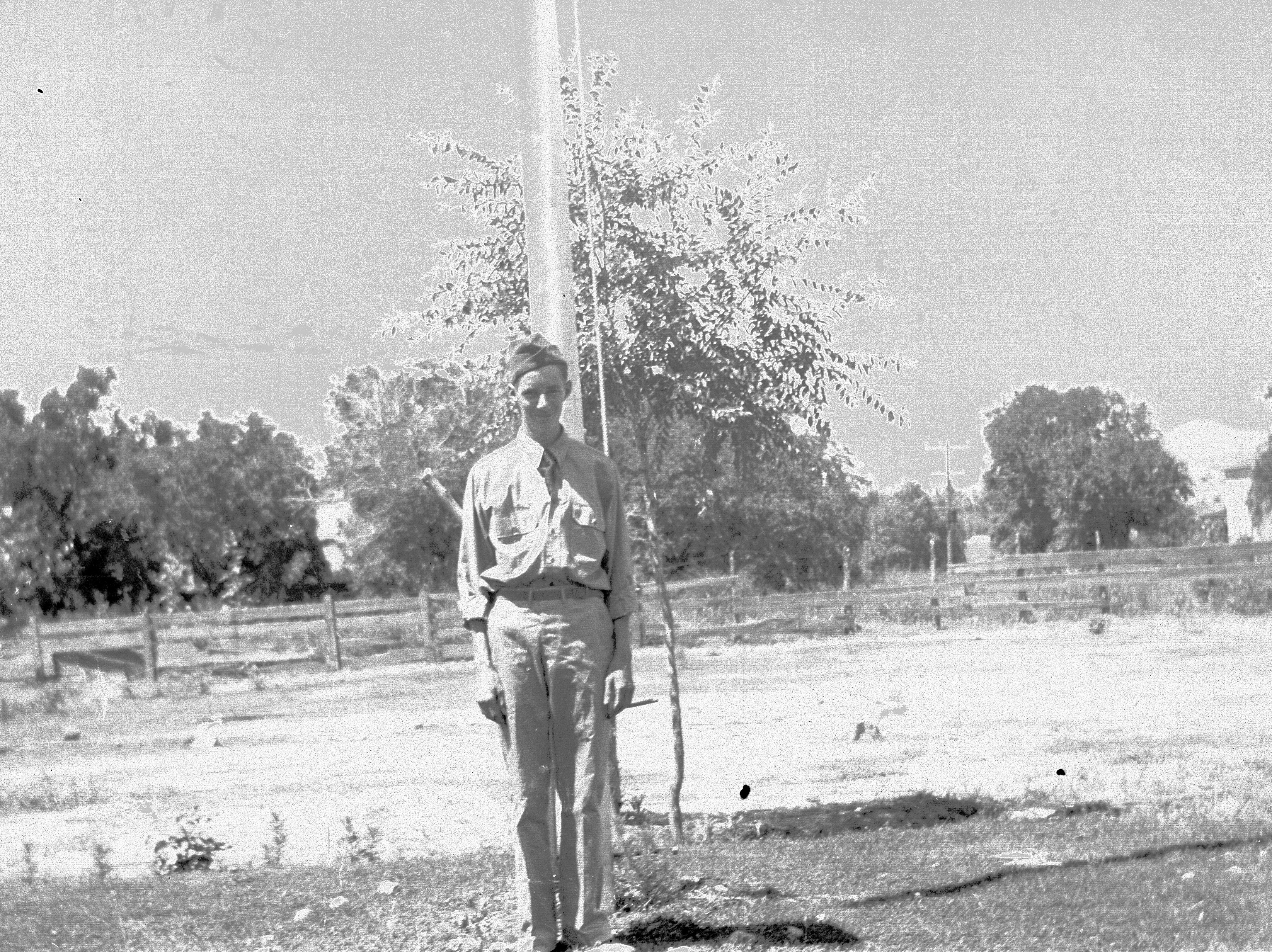 An enrollee standing in front of the flagpole at the Leeds CCC Camp