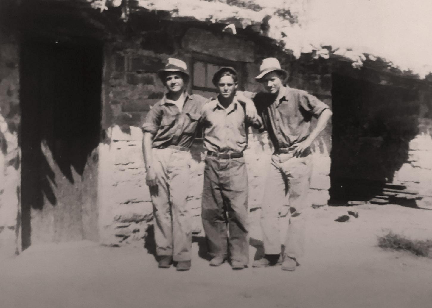 Three enrollees in front of a rock building at the St. George CCC Camp